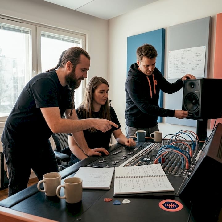 Team collaborating around studio mixing console