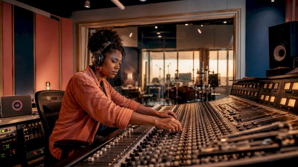 Audio engineer adjusting mixing console in studio