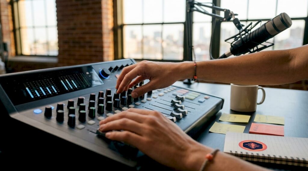 Hands adjusting podcast audio mixing console
