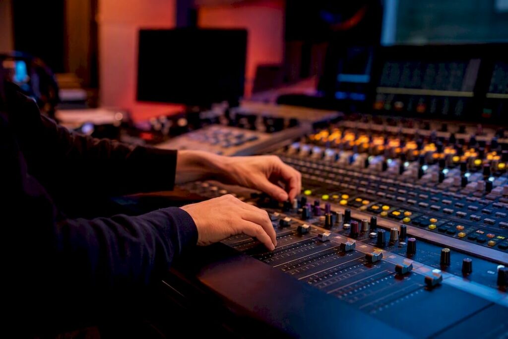 Hands adjusting mixing console faders