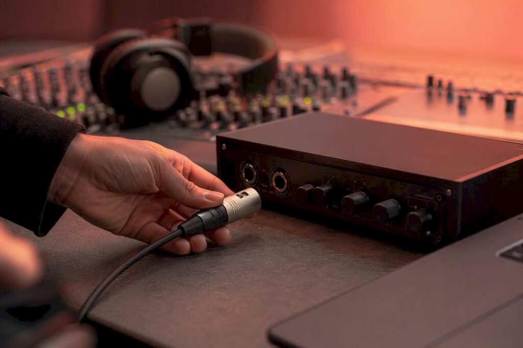 Hands plugging cable into audio interface