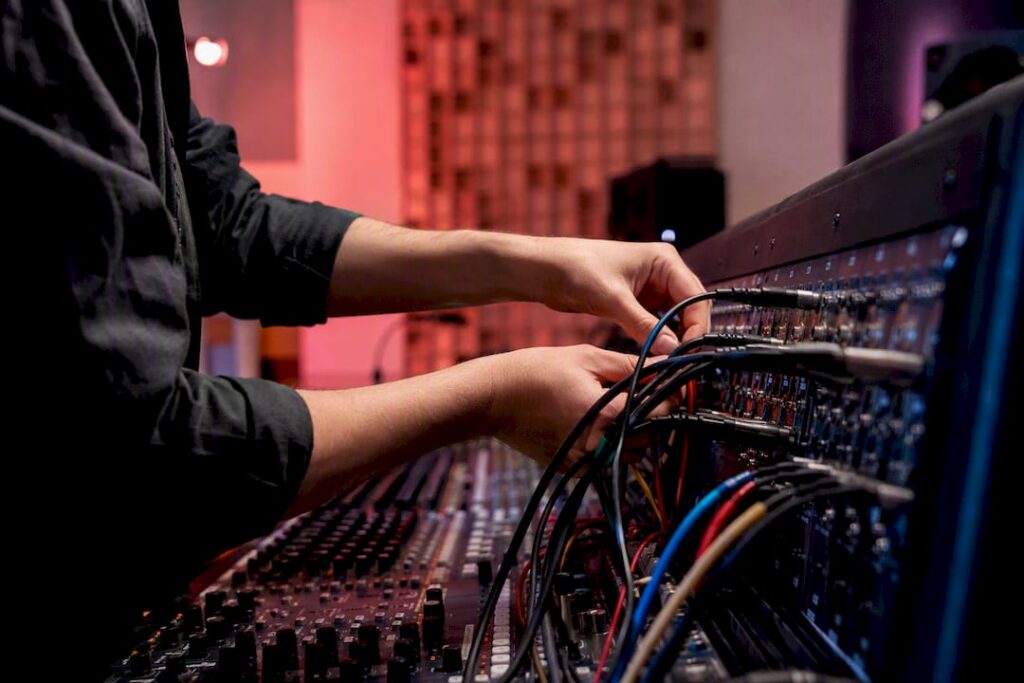 Hands plugging audio cables into mixing desk